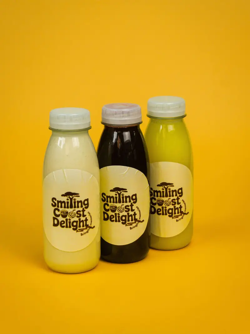 Three bottled cold-pressed drinks standing on a yellow backdrop