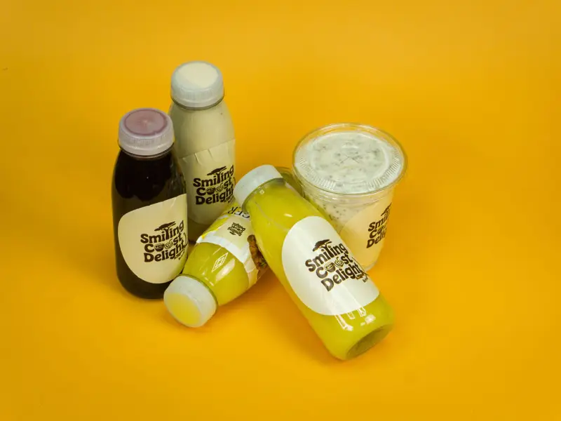 Bottled drinks and a cup of chia pudding arranged together on a yellow backdrop